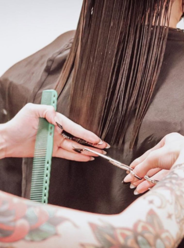 Stylist performing a precision straight hair cut on long dark hair at Ella Rose Hair Boutique in Albuquerque, NM.