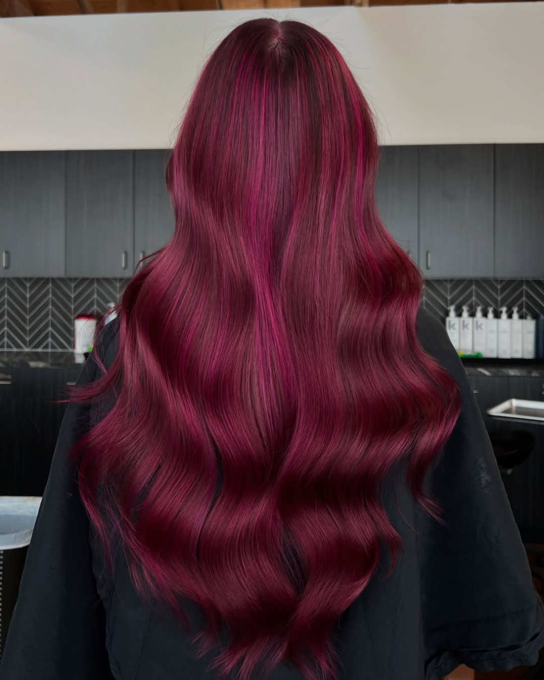 Back view of a woman with long, deep yet vibrant berry pink hair
