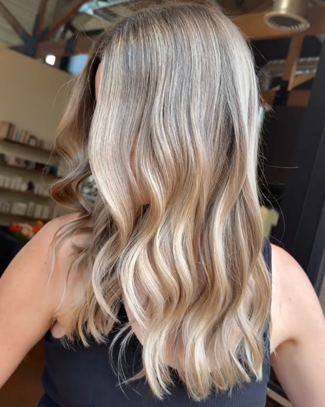 Side view of woman with dimensional, bright and blended blonde hair and a soft smoky root