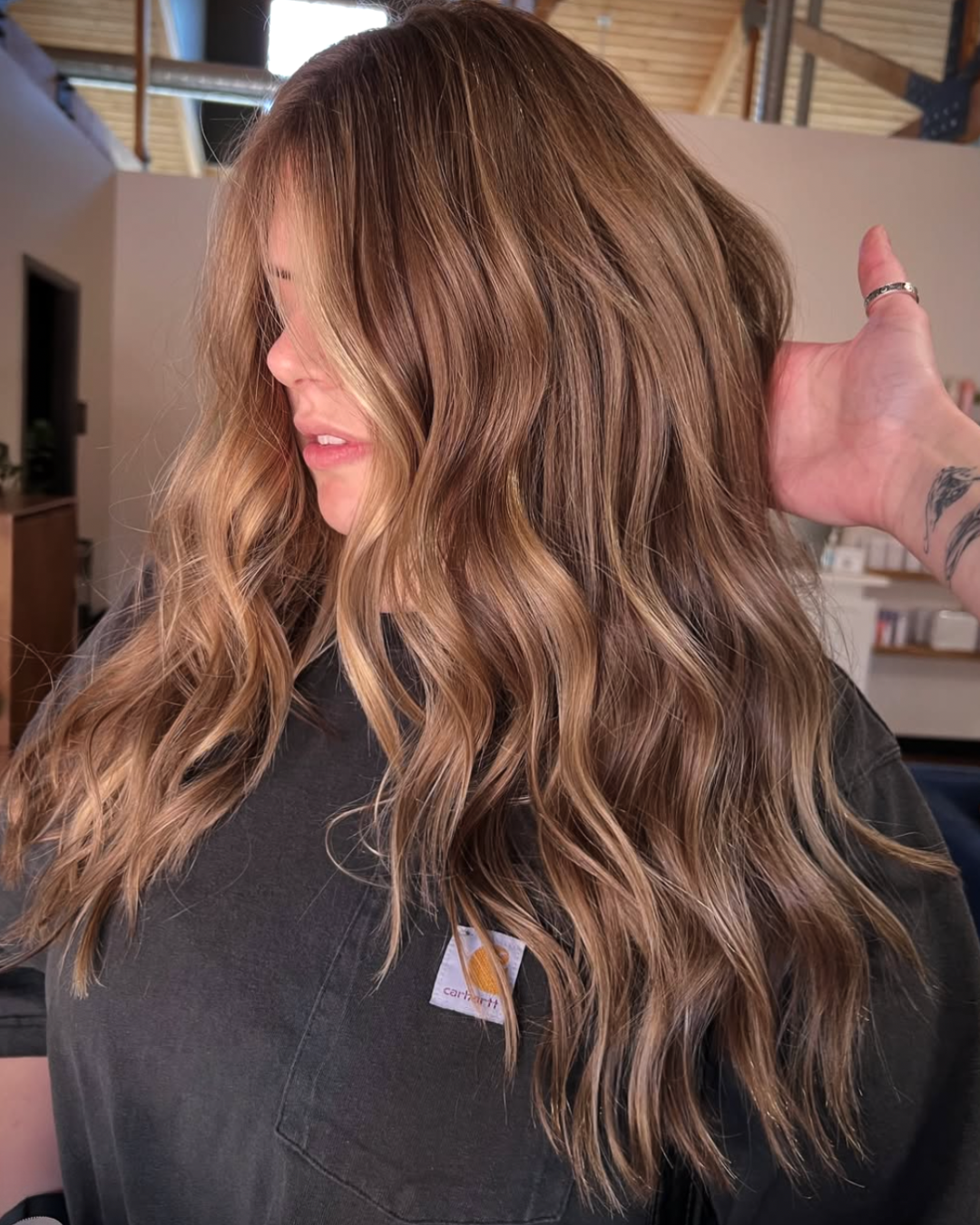 Woman with long wavy bronde balayage hair featuring blended brunette and blonde tones.