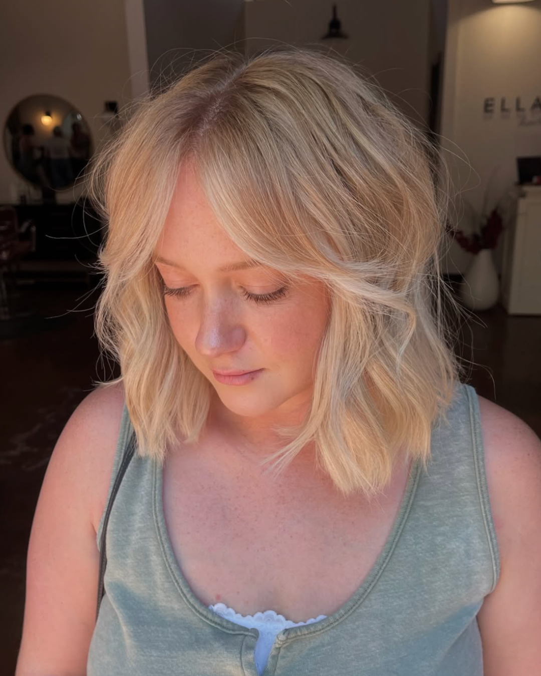 Woman with short hair and curtain bangs featuring a buttery, soft blonde color