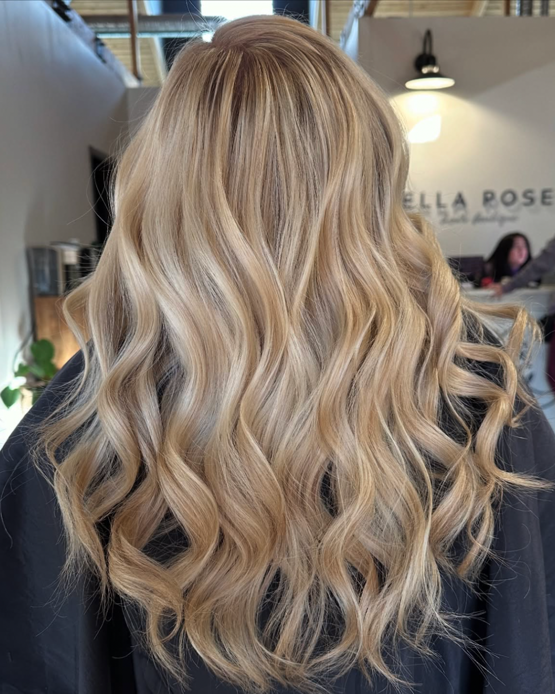 Back view of a woman with medium length hair and soft, buttery blonde blended tones throughout