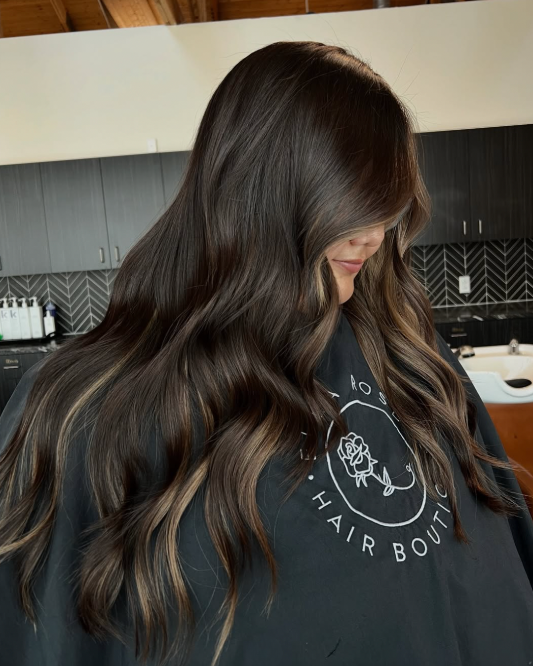 Side view of a woman with dark brown hair and caramel highlights