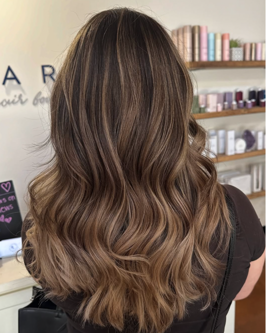 Back view of a woman with dark brunette hair and added caramel highlights for a dimensional look