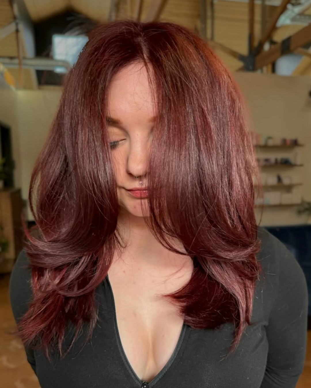 Woman with chest length hair and face framing layers with deep cherry cola red color