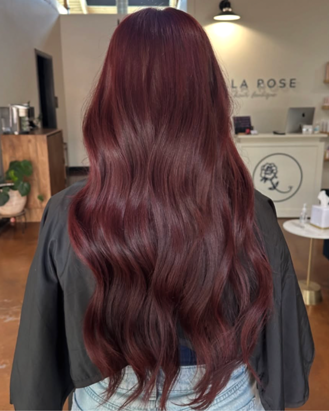 Back view of a woman with long, wavy, rich cherry cola colored hair