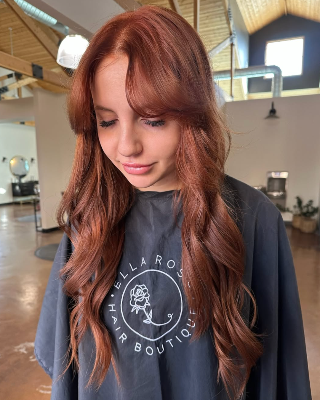 Woman with long hair and curtain bangs, featuring a natural copper color