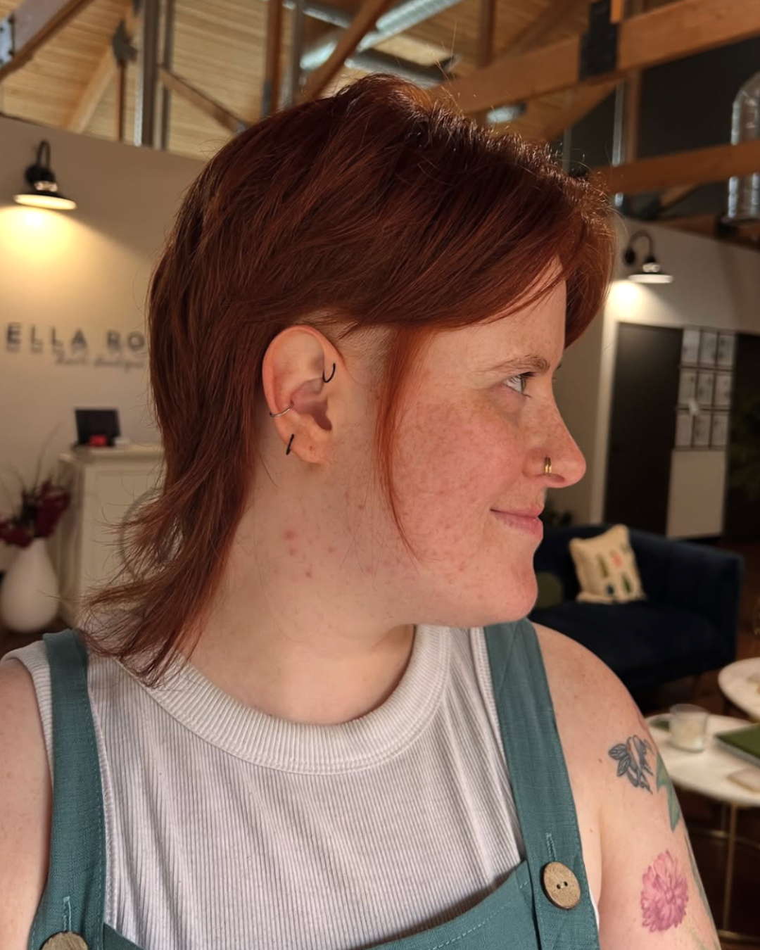 Woman with a copper red mullet haircut featuring short layers around the face and longer length in the back.