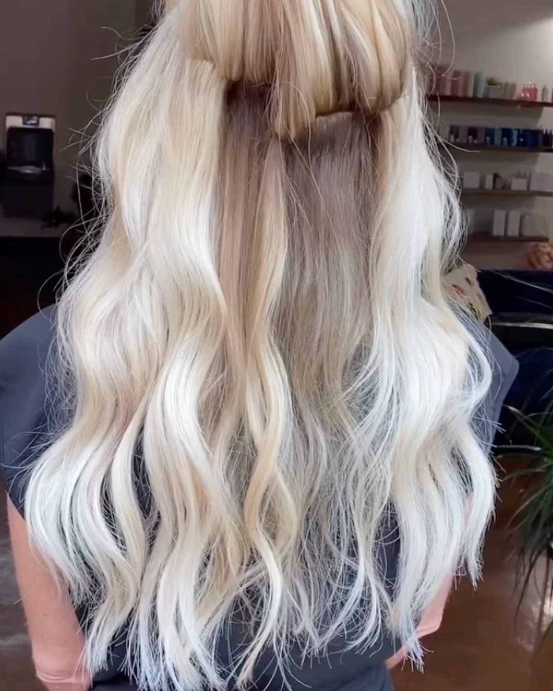 Back view of a woman showing a seamless install of custom dimensional bright blonde extensions for added length and volume.