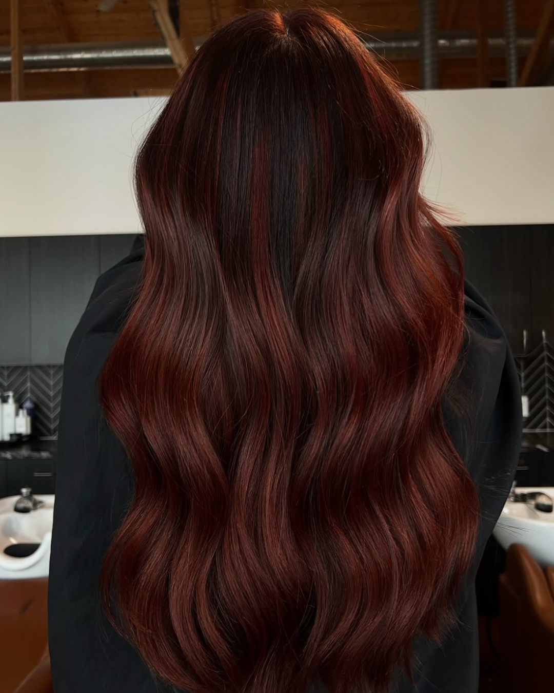 Back view of a woman with long hair in a dark, dimensional auburn color