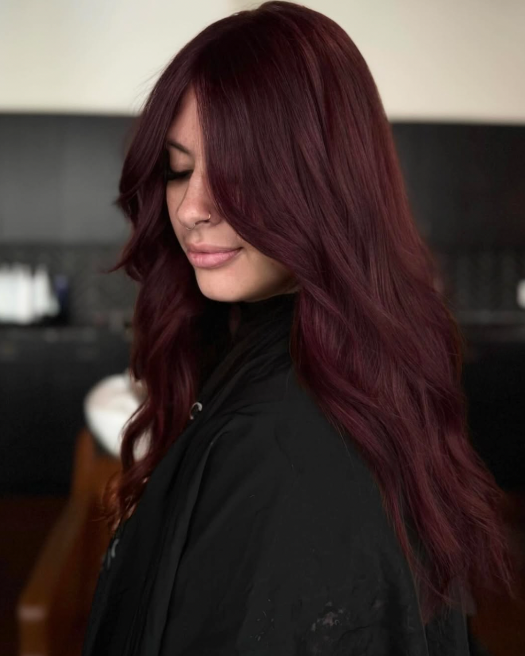Woman with deep, yet vibrant maroon colored hair with long layers
