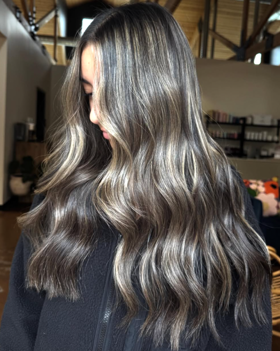 Woman with long wavy hair featuring a dimensional, deep ashy brunette color
