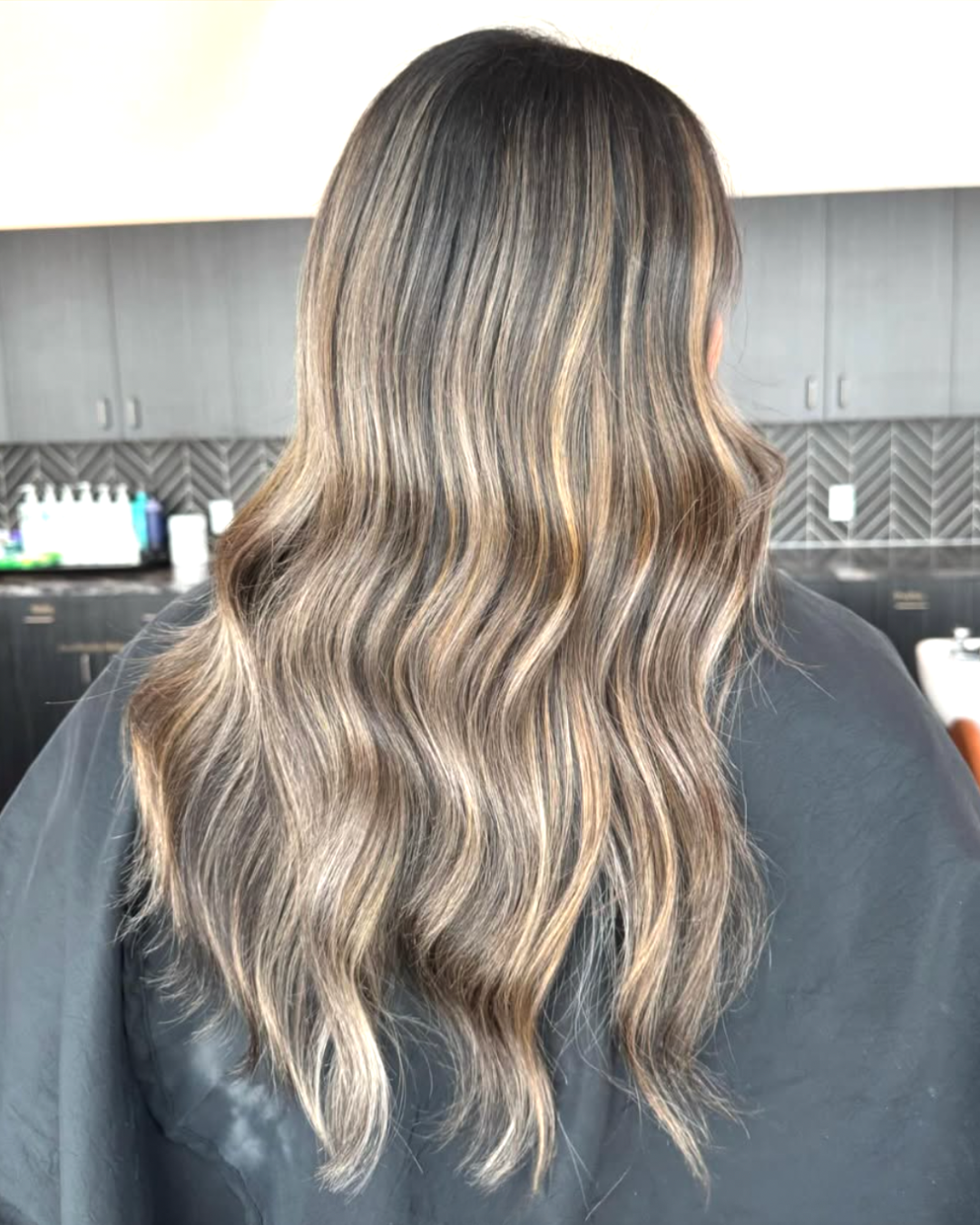 Back view of a woman with long hair featuring a beige, dimensional balayage