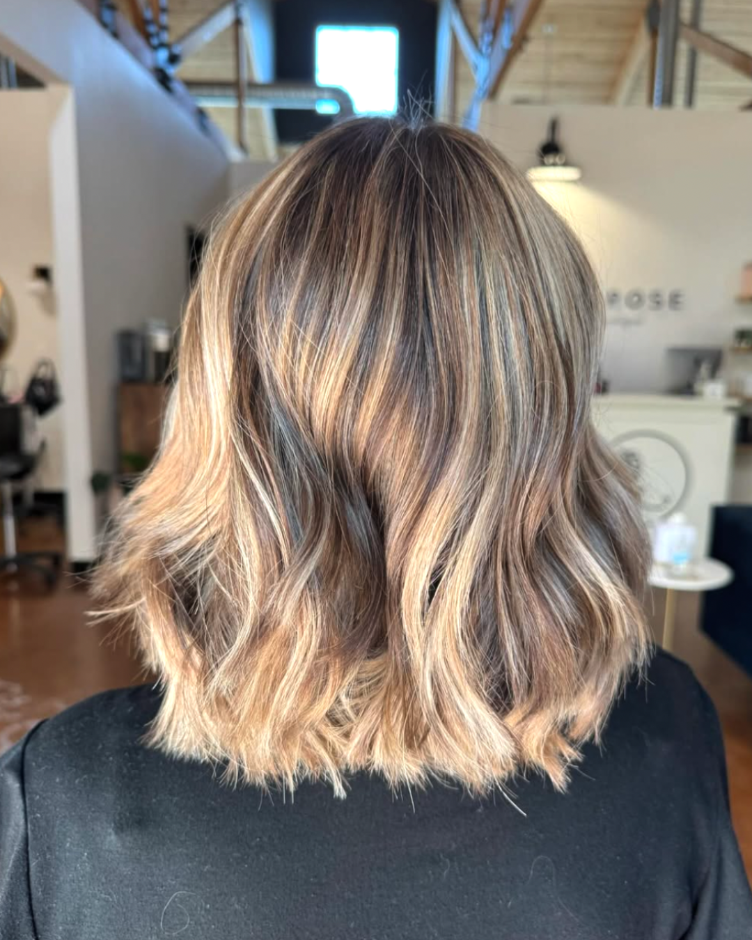 Back view of a woman with short, dimensional blonde hair featuring light blond highlights