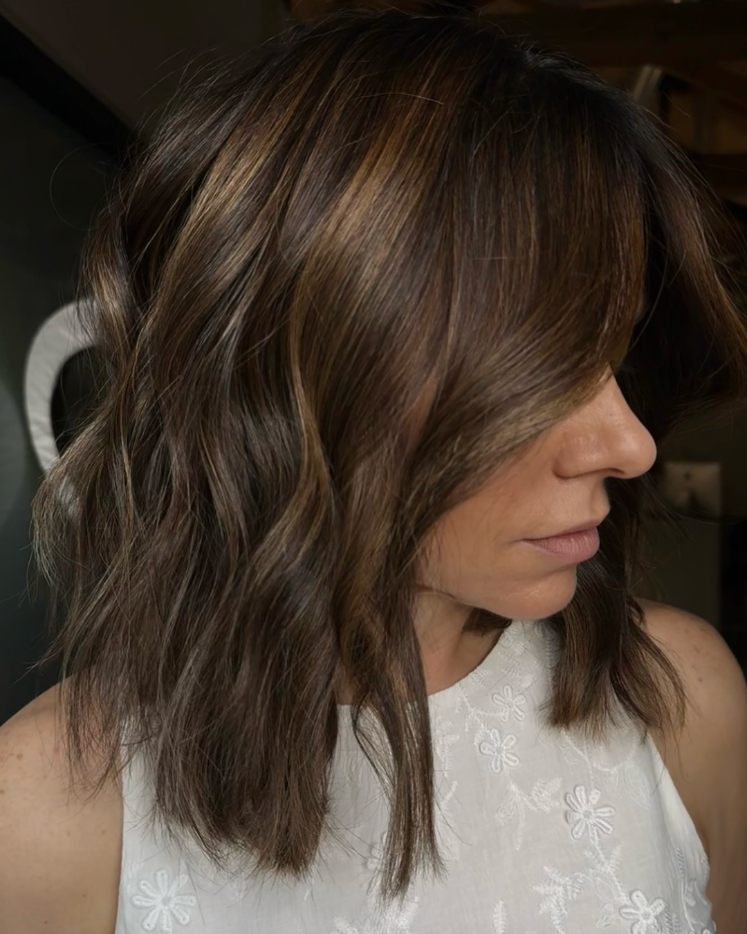 Woman with shoulder length, wavy brunette hair with highlights