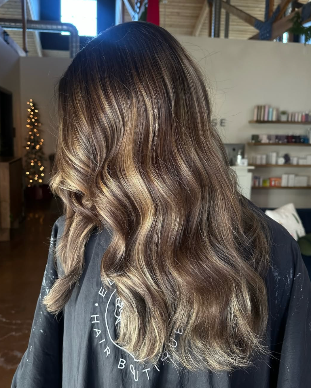 Side view of a woman with long brunette hair and blonde highlights throughout for a dimensional look