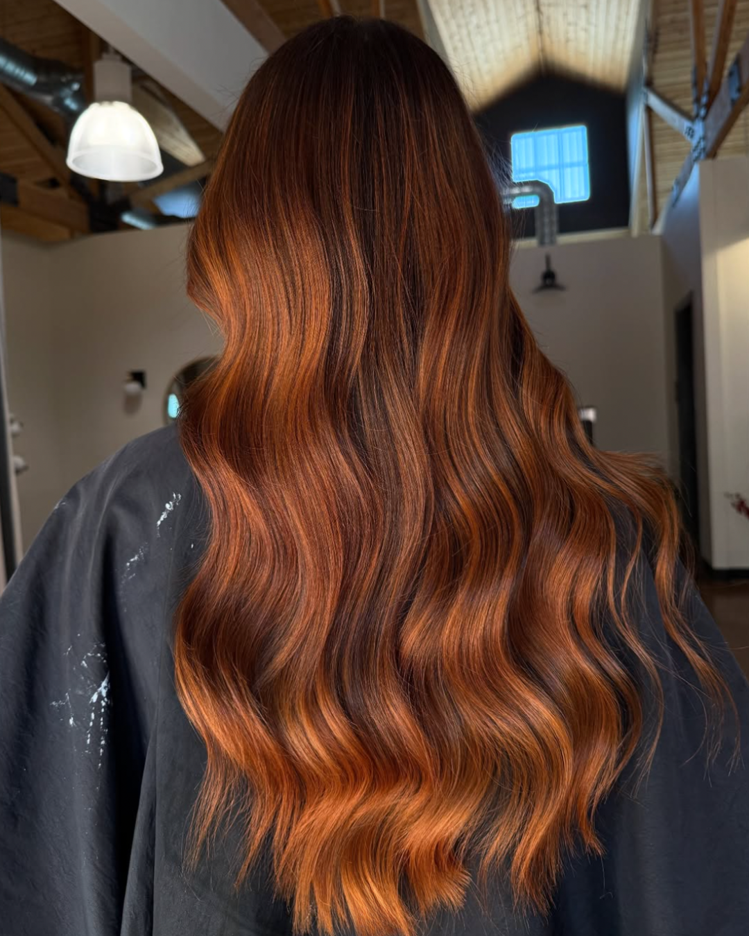 Back view of a woman with long hair and dimensional, rich copper tones
