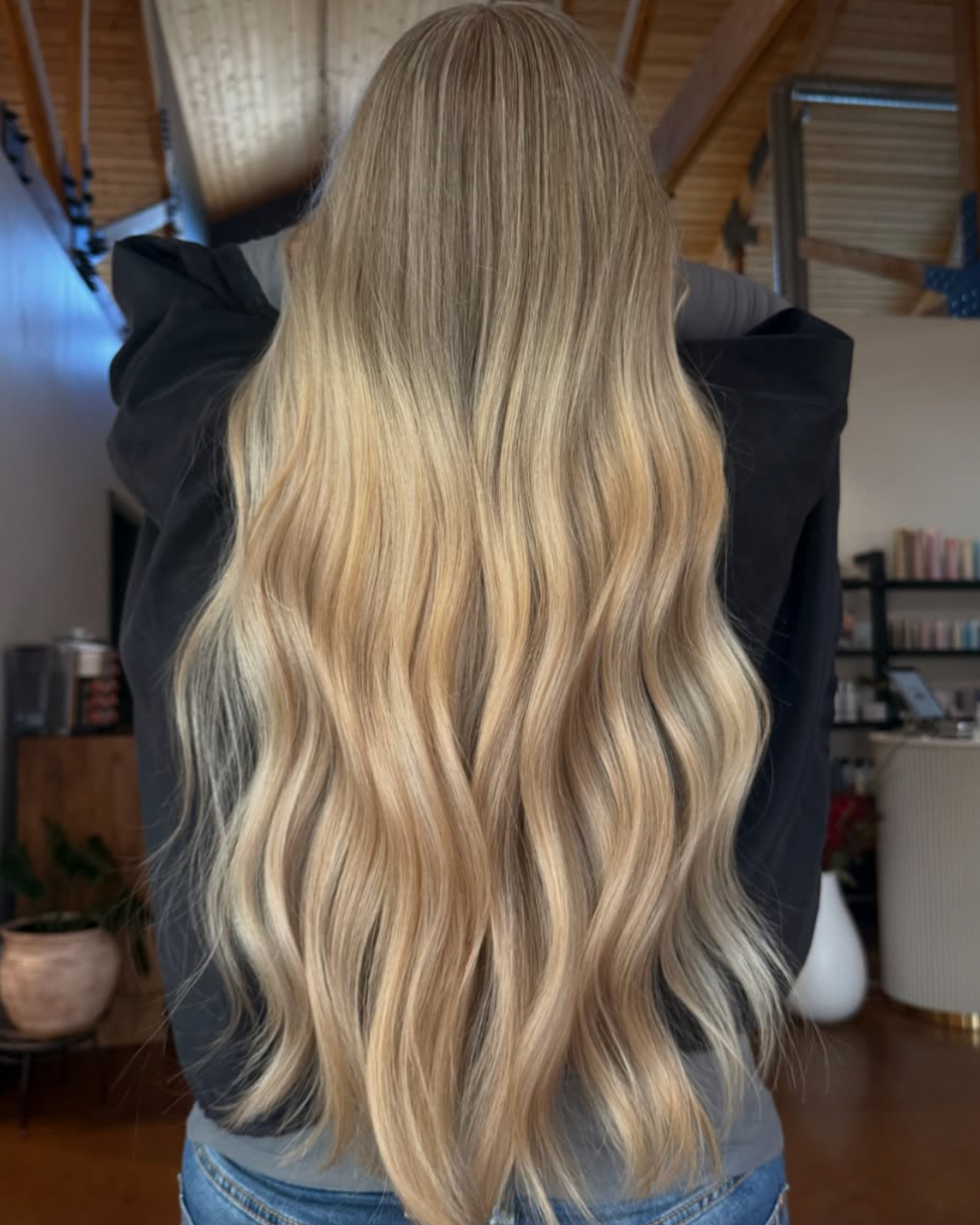 Back view of a woman with long, golden blonde hair and highlights