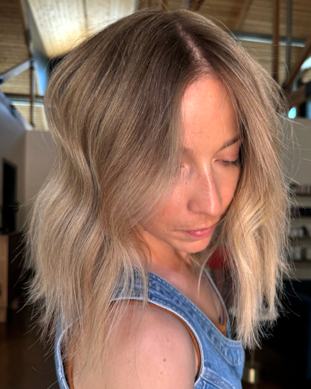 Woman with shoulder length hair thatis golden blonde and lived in with a darker root and dimension