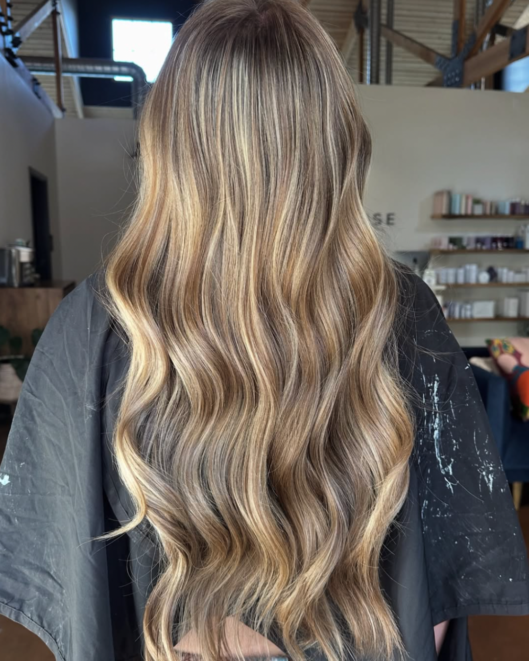 Back view of a woman with deep blonde hair featuring blended highlights as she gradually transitions from brunette to blonde.