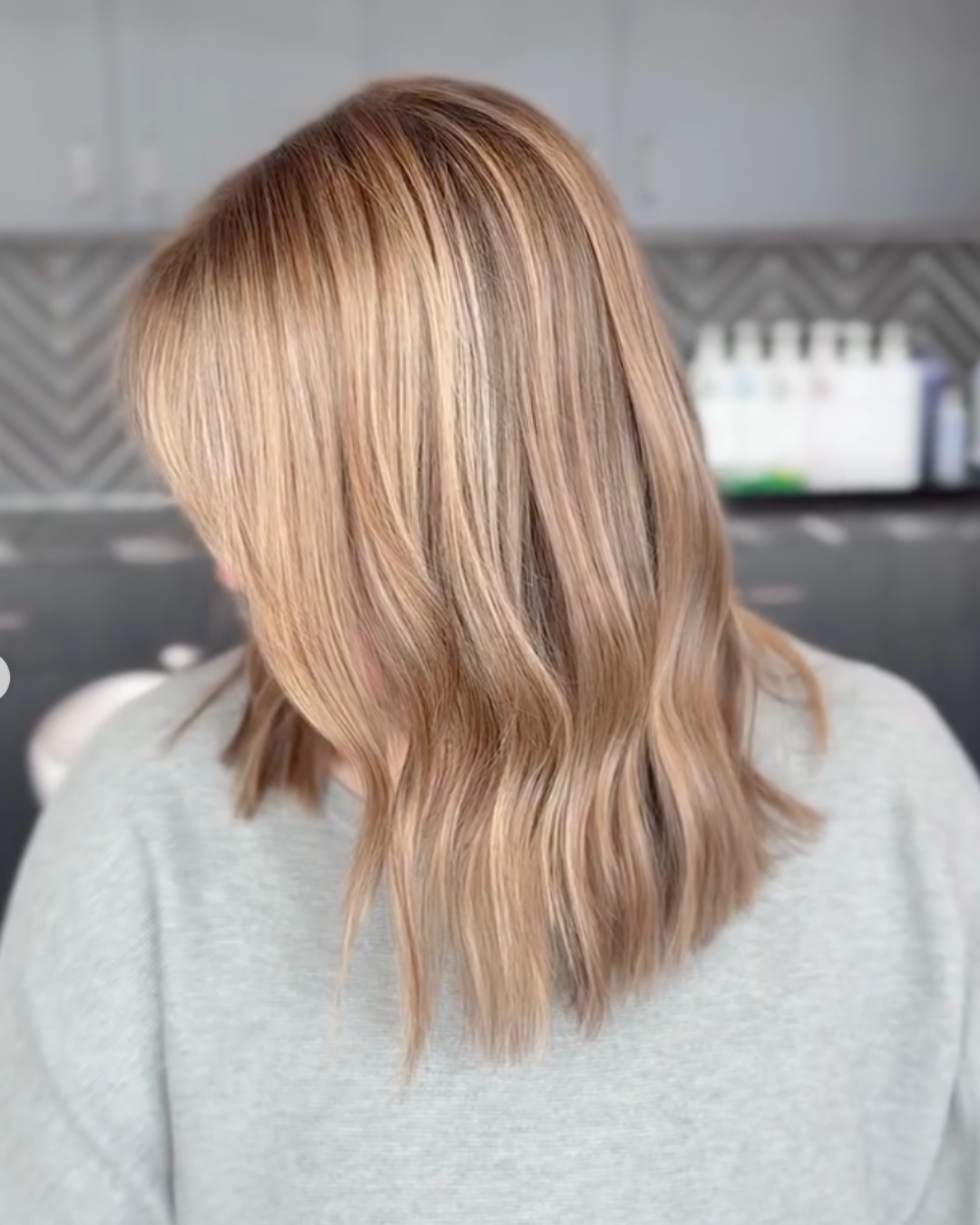 Side view of a woman with shoulder-length blonde hair with soft grey blending and natural dimension.