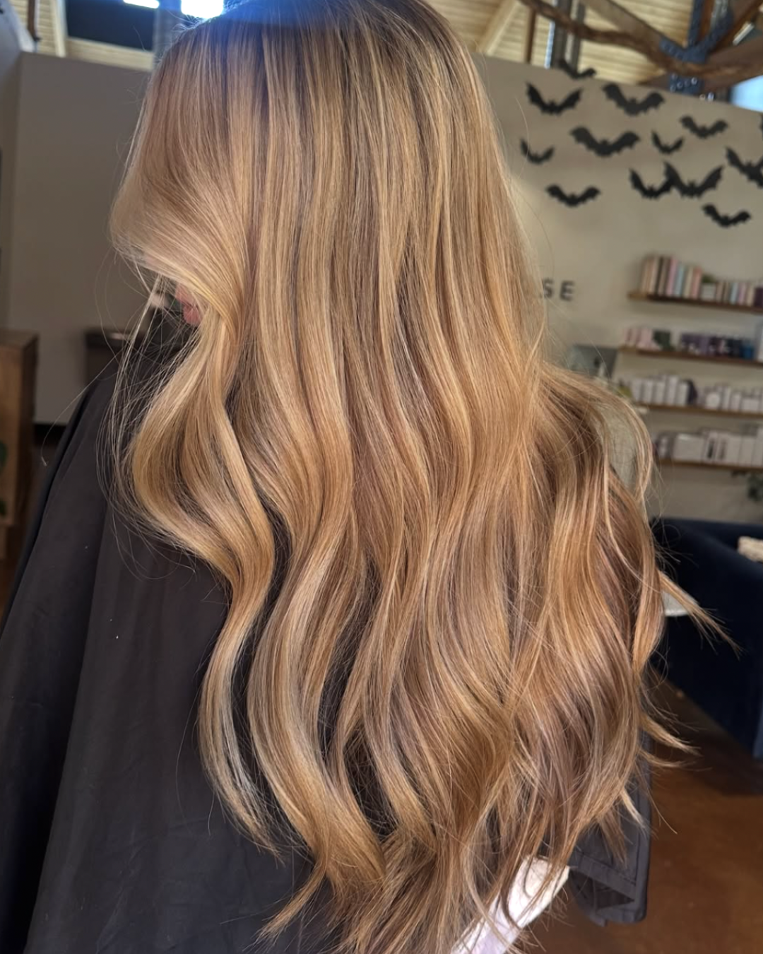 Back view of a woman with long, honey blonde hair and light blonde highlights