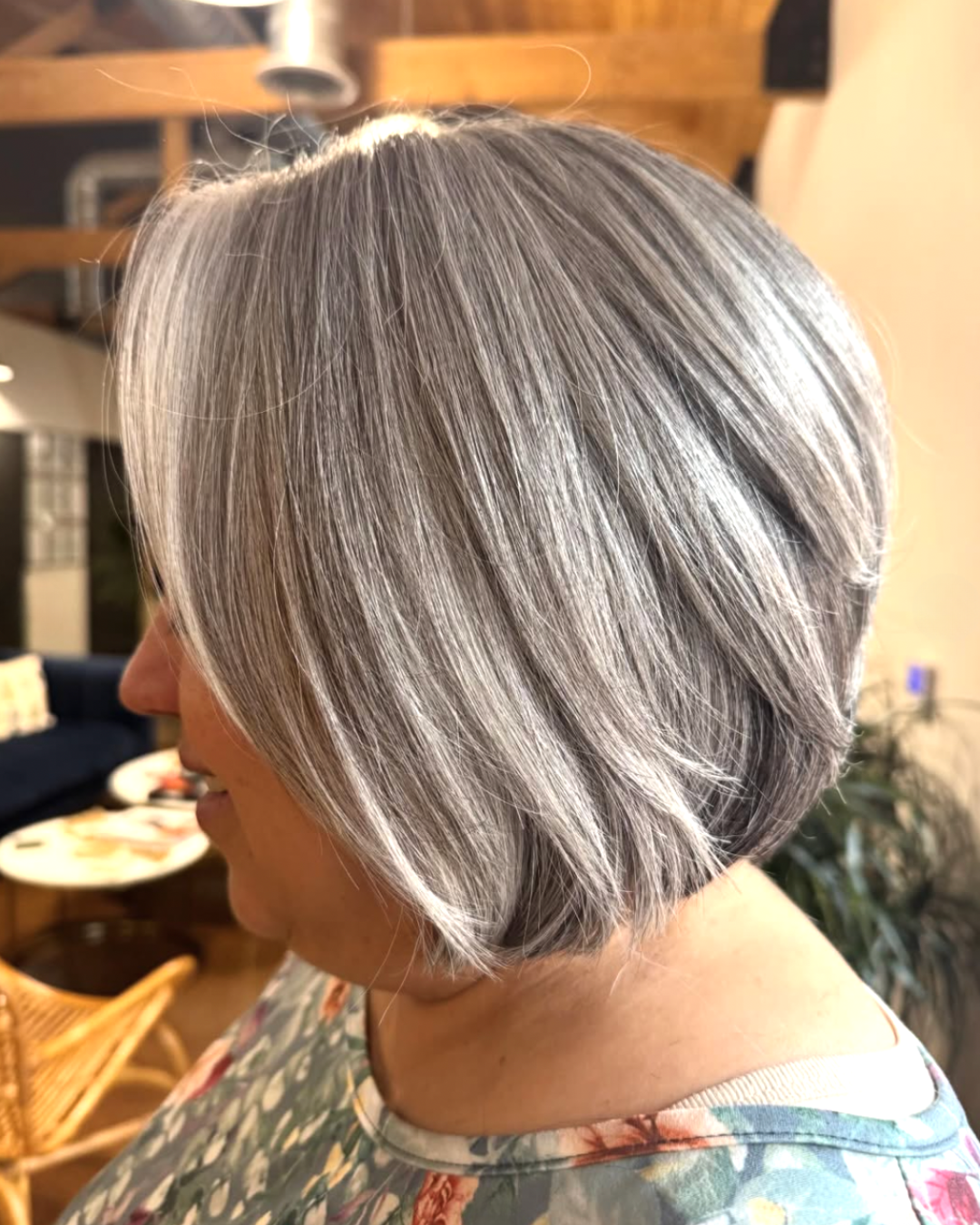 Side view of a woman with dimensional silver hair and a layered, short bob haircut