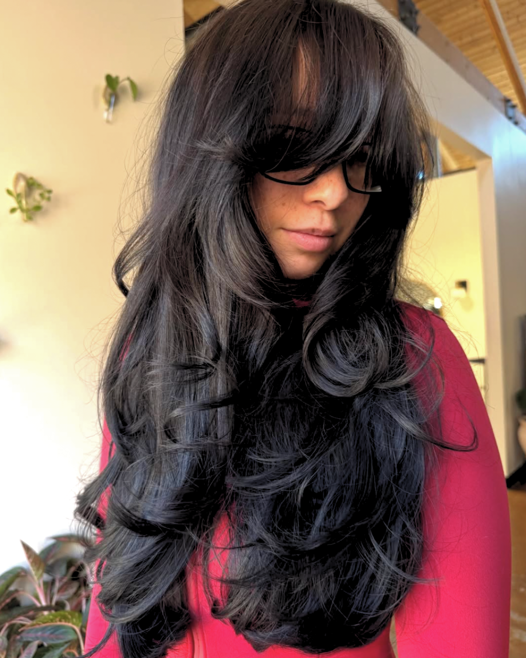 Woman with long black hair with full bangs and visible short and long layers