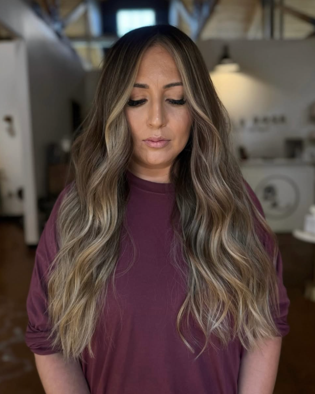 Woman with long lived-in blonde hair featuring blended highlights, natural root depth, and soft waves.