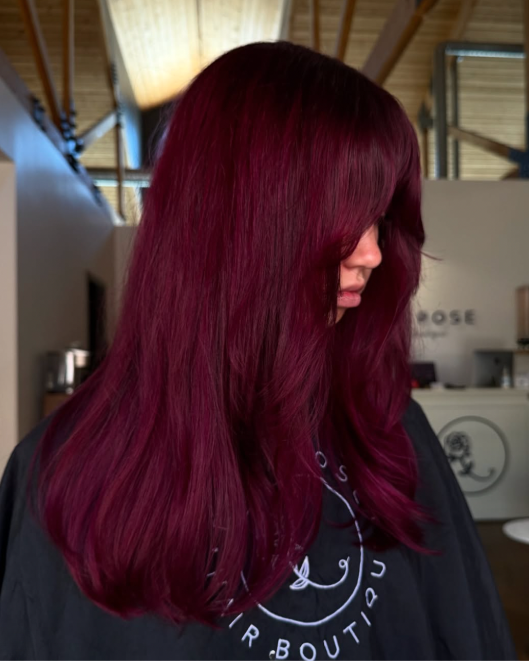 Side view of a woman with medium-long length hair in a deep magenta color