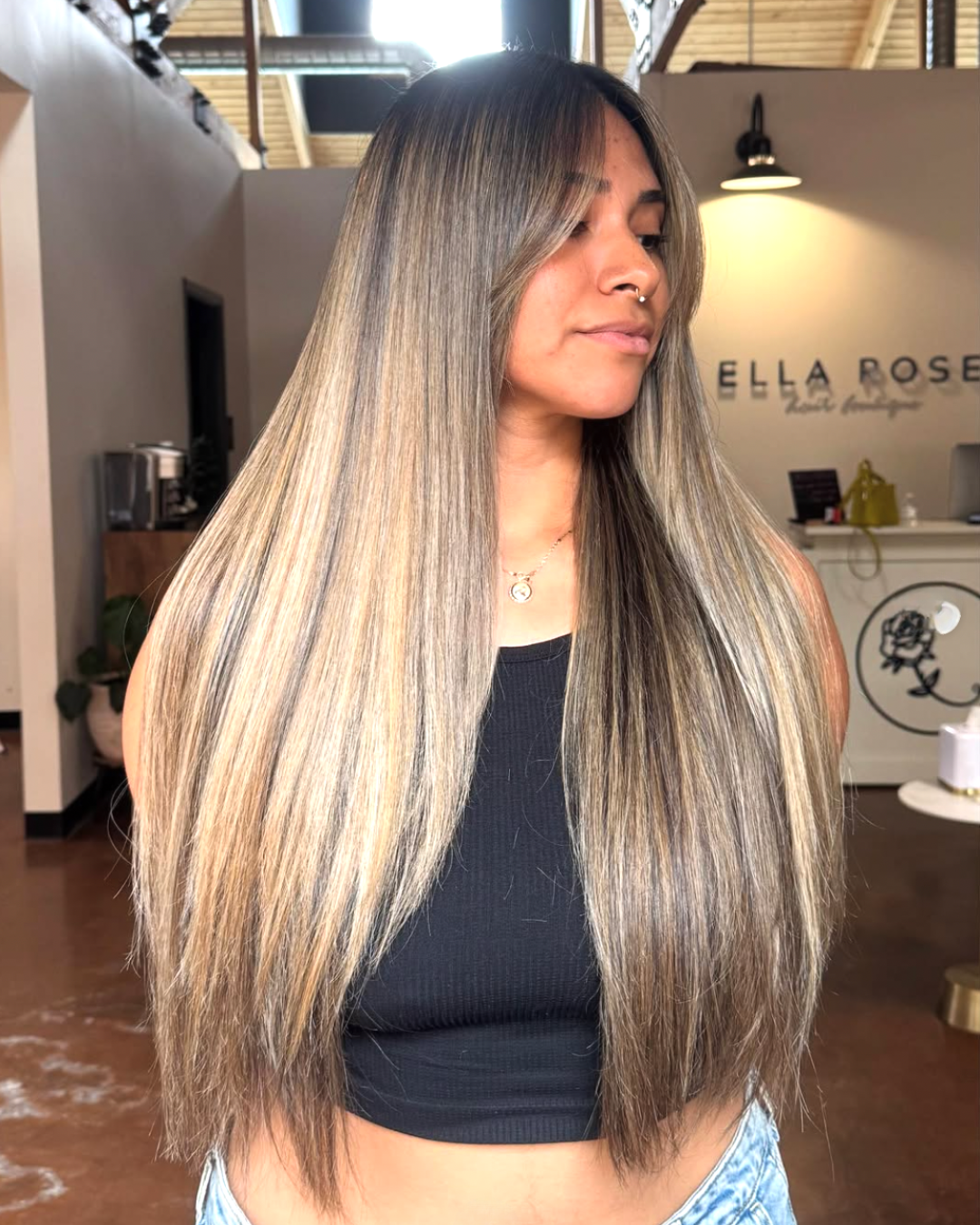 Woman with very long hair and curtain bangs featuring a mushroom brunette color with darker roots and lighter end