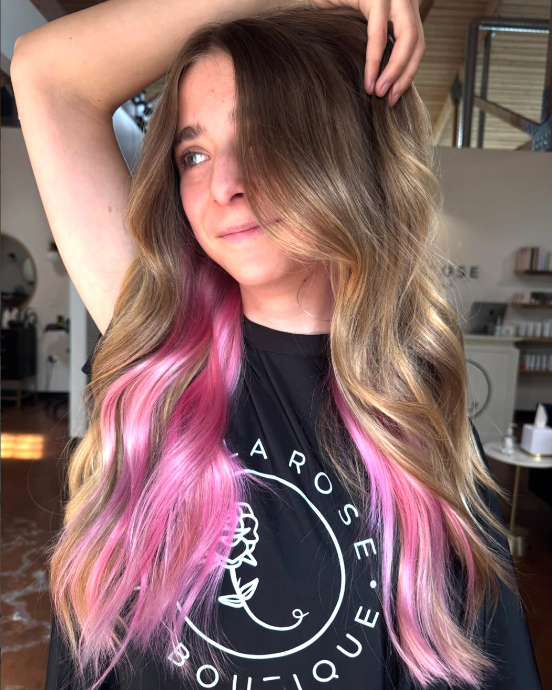 Woman with long bronde wavy hair with light and vivid pink color underneath for a peekaboo look