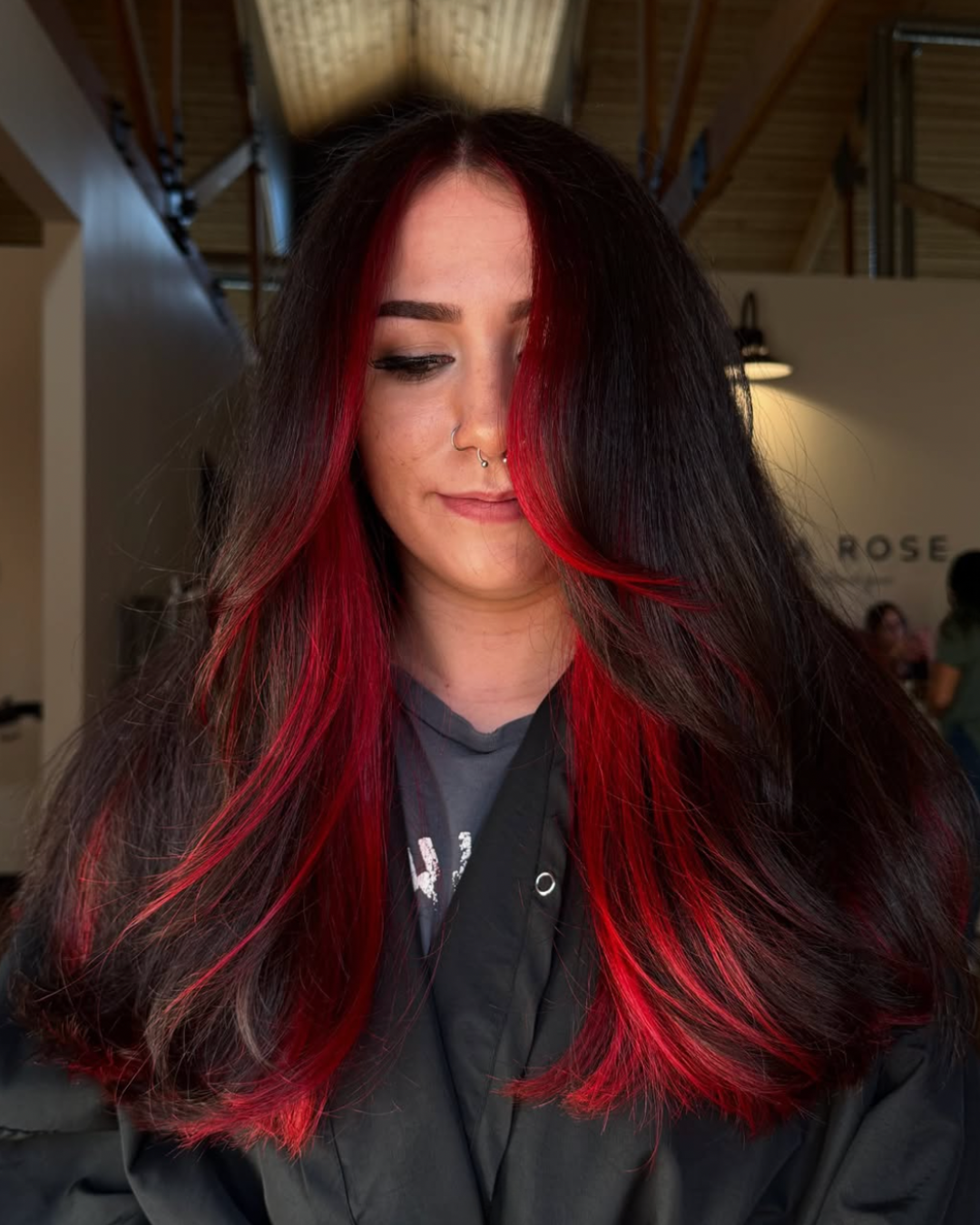 Woman with long, dark brunette layered hair featuring vivid red face framing pieces