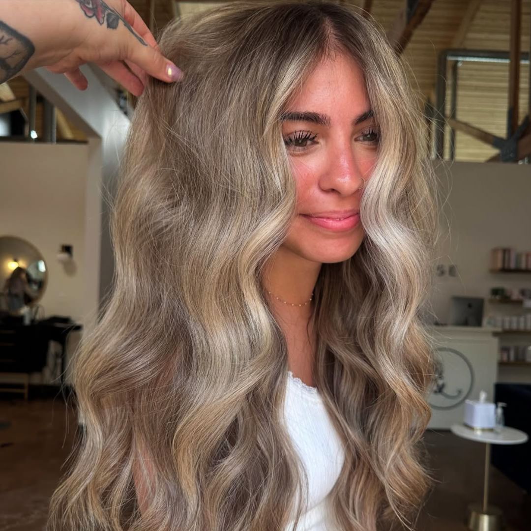 Woman with a smokey blonde balayage with bright blonde face framing