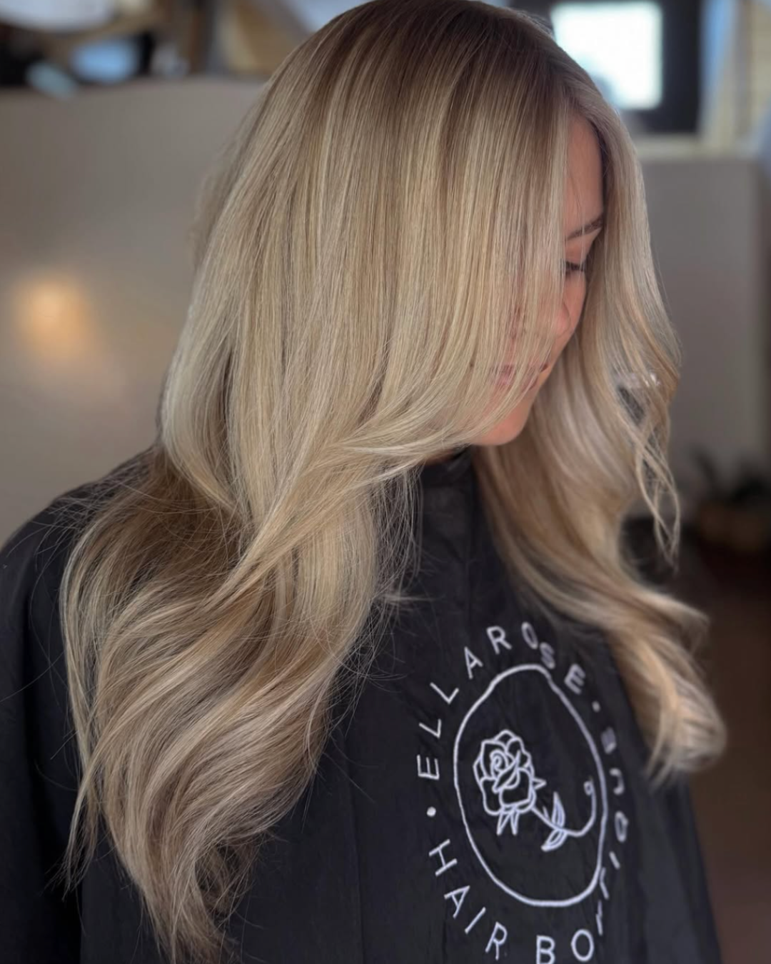 Woman with long soft blonde hair featuring blended creamy blonde tones with smooth, voluminous waves.