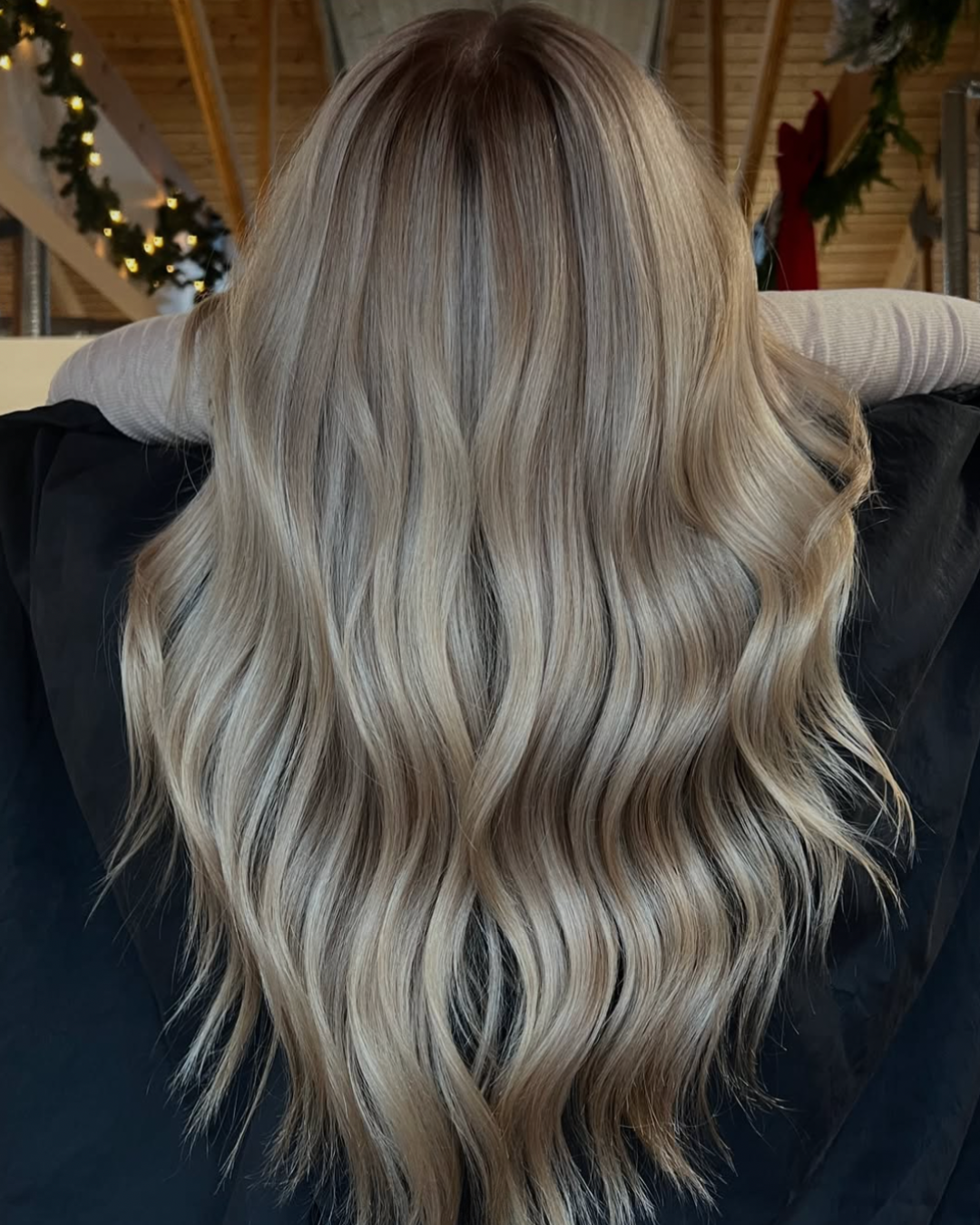 Back view of a woman with long blonde hair featuring dimension with highlights throughout and a darker toot
