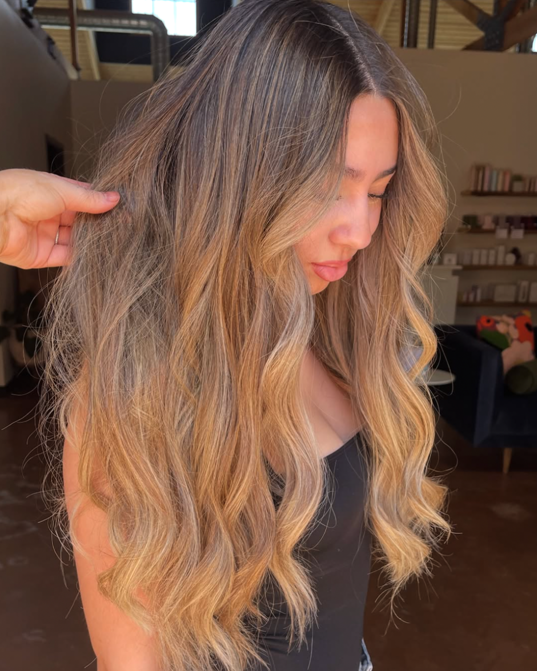 Side view of a woman with sun kissed bronde hair featuring a darker root and lighter blonde going down
